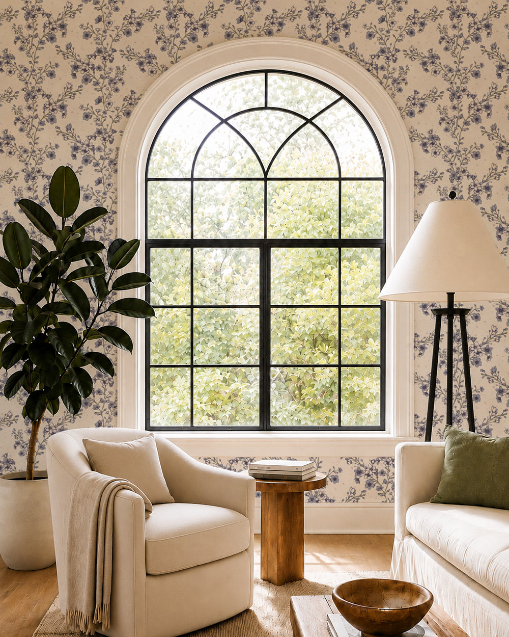 Blossom Whisper Dusty Blue floral wallpaper in a living room with an arched window, cream seating and natural wood accents.