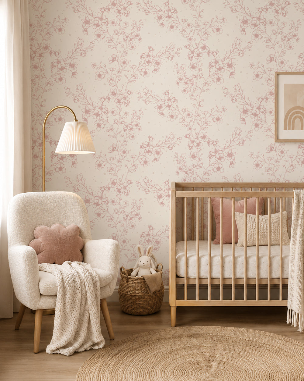 Blossom Whisper Dusty Rose floral wallpaper in a soft nursery with a natural wood crib, cream armchair and blush accents.