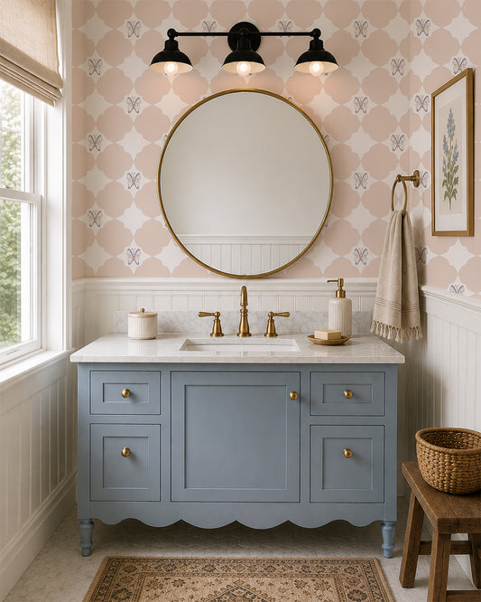 Keepsake Blush wallpaper in an elegant bathroom with a dusty blue vanity, brass fixtures and white paneling.