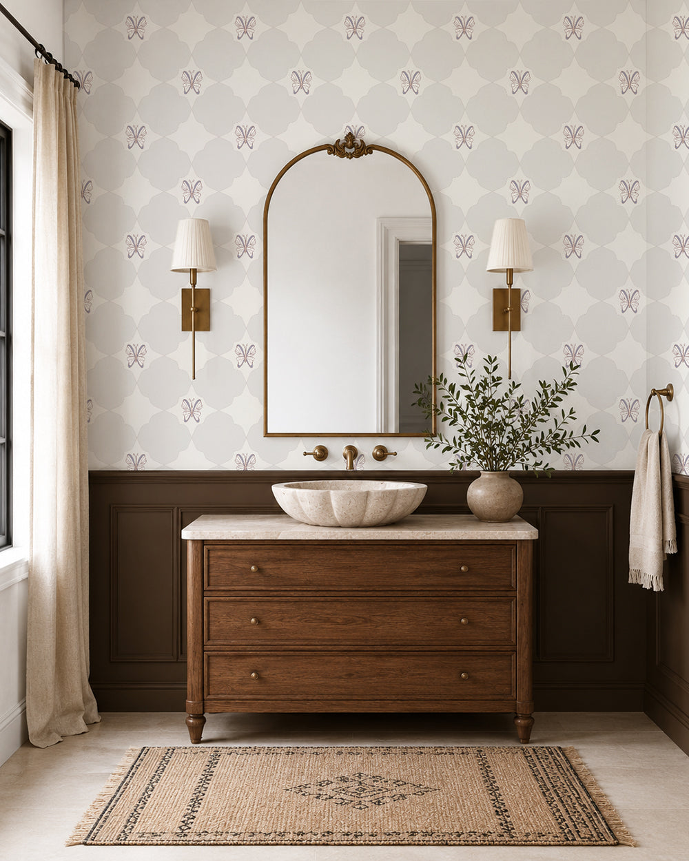 Keepsake Linen wallpaper in an elegant bathroom with a wood vanity, dark wainscoting and brass sconces.