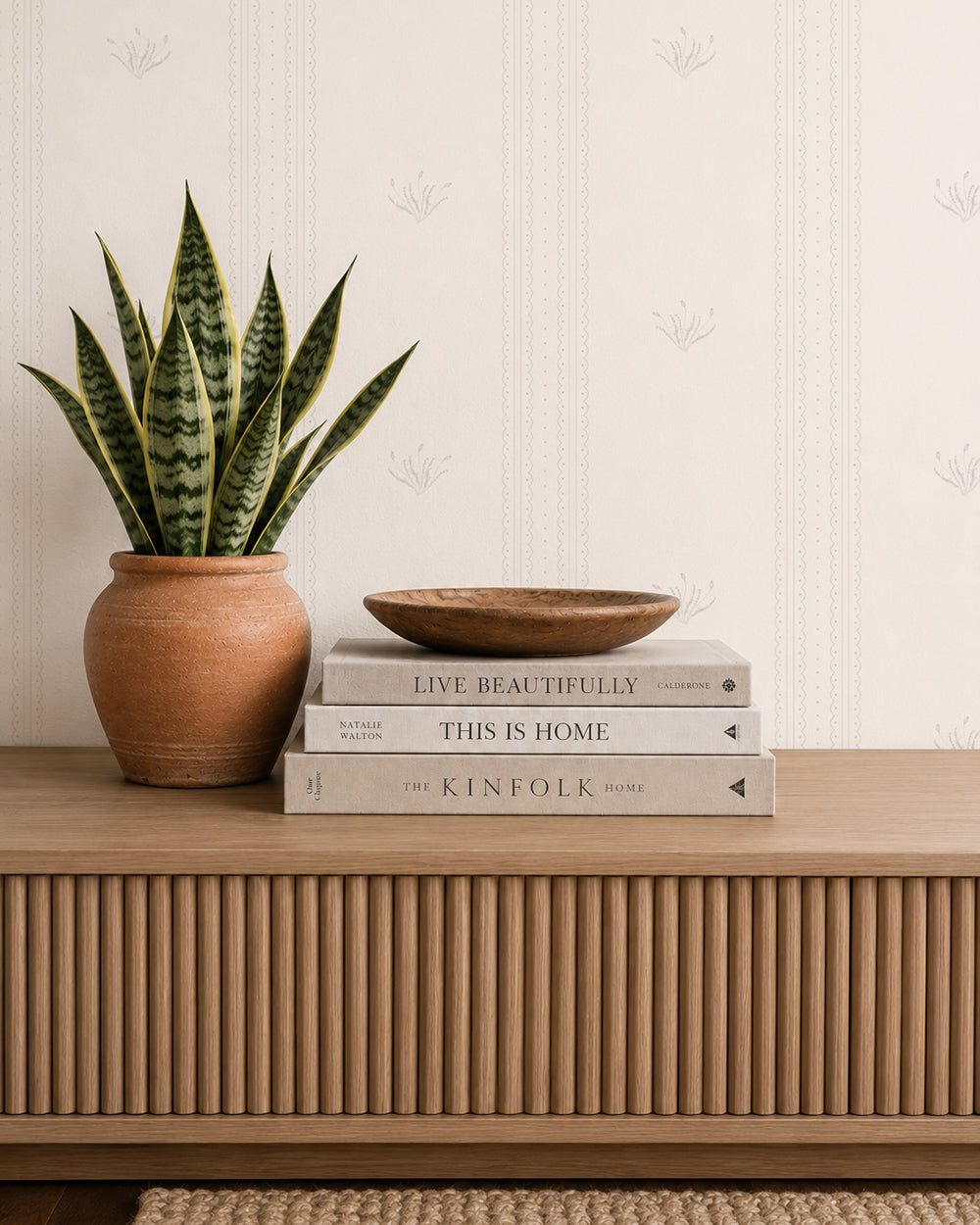 Lace Garden Linen wallpaper behind a wood console with books, a snake plant and warm neutral decor.