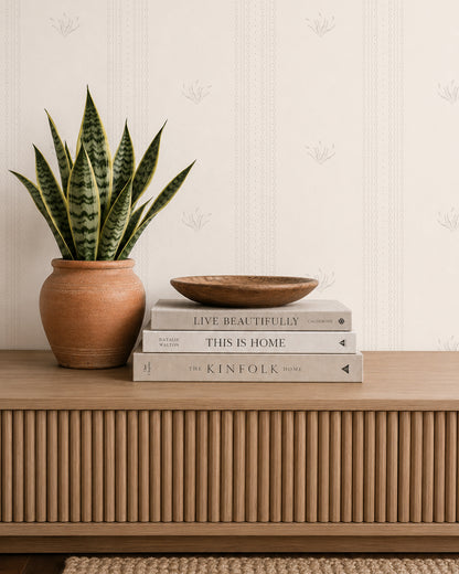 Lace Garden Linen wallpaper behind a wood console with books, a snake plant and warm neutral decor.