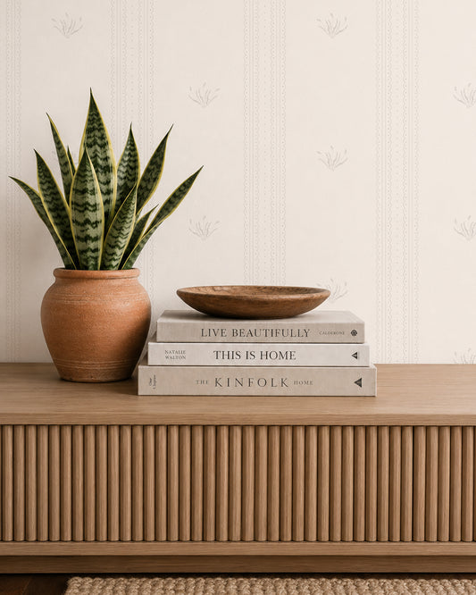 Lace Garden Linen wallpaper behind a wood console with books, a snake plant and warm neutral decor.