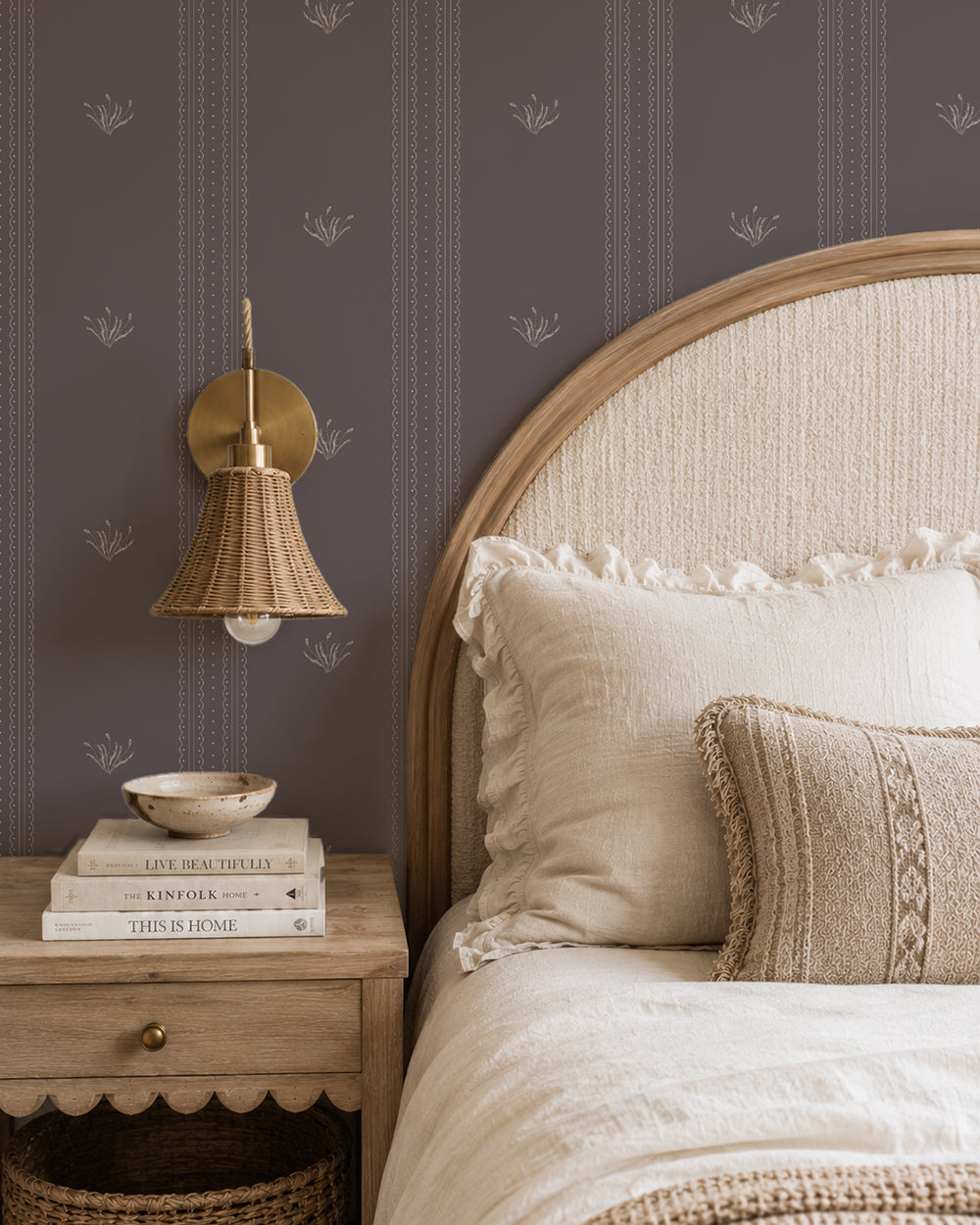 Lace Garden Warm Brown wallpaper in a cozy bedroom with a curved wood headboard, cream bedding and woven lighting.