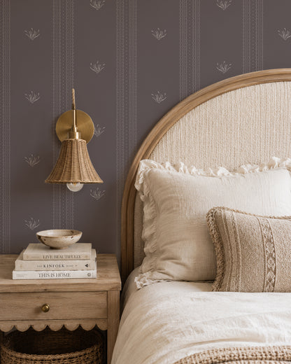 Lace Garden Warm Brown wallpaper in a cozy bedroom with a curved wood headboard, cream bedding and woven lighting.