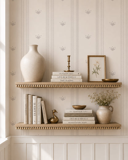 Lace Garden Warm Brown wallpaper behind styled shelves with books, pottery and warm brass accents.