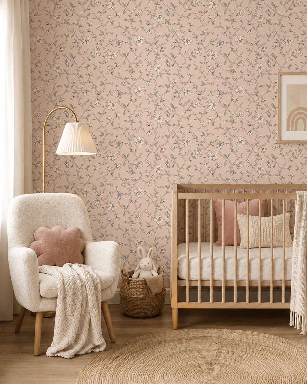 Magnolia Bloom Blush wallpaper in a soft nursery with a natural wood crib, cream armchair and blush accents.