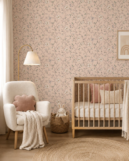 Magnolia Bloom Blush wallpaper in a soft nursery with a natural wood crib, cream armchair and blush accents.