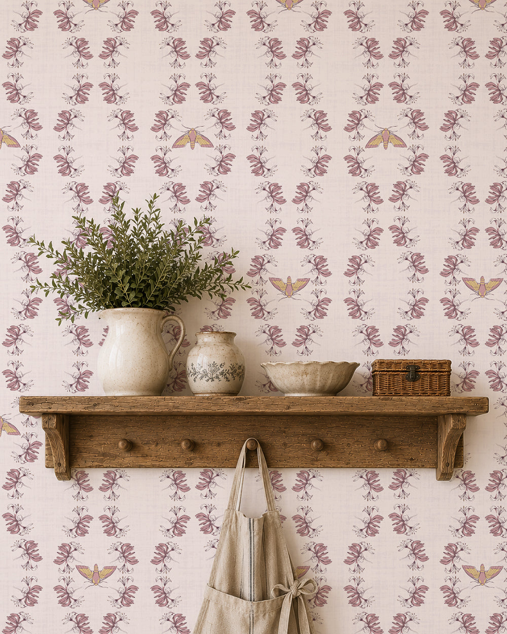 Night Bloom Soft Blush wallpaper behind a rustic wood shelf with greenery, pottery and warm natural accents.