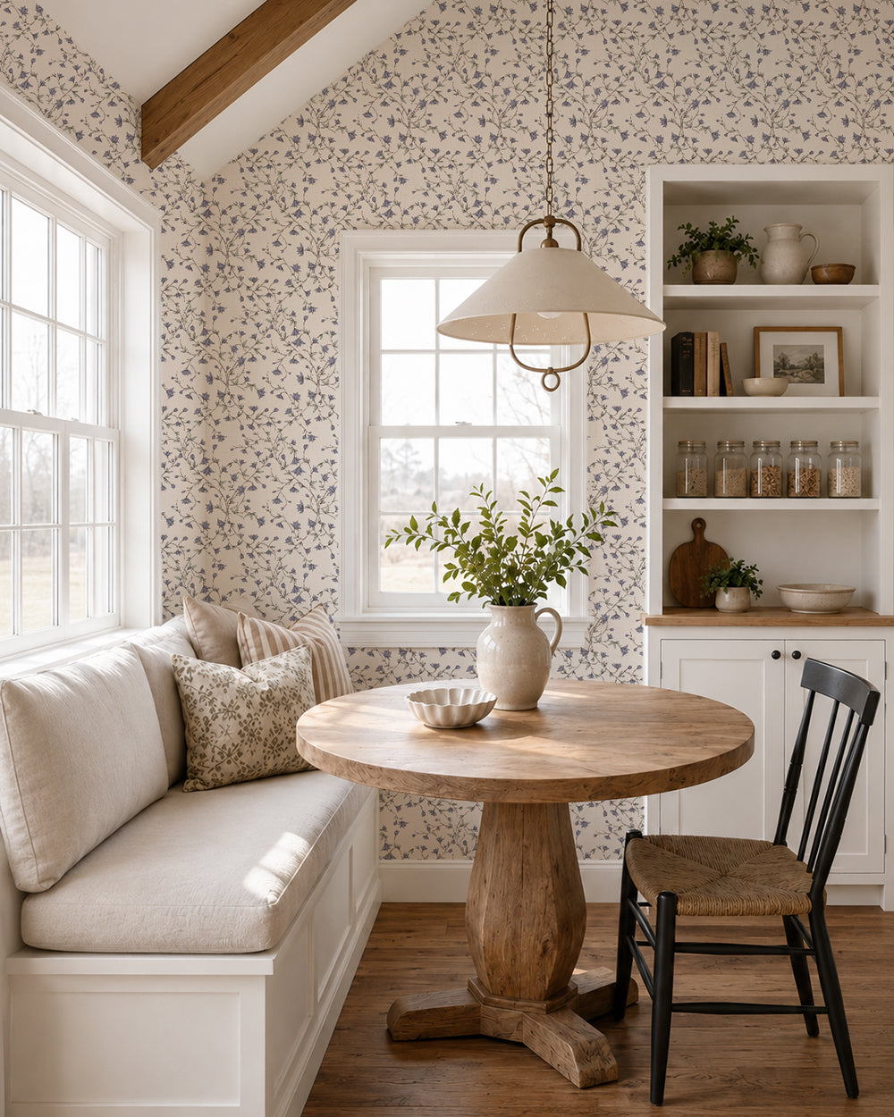 Spring Vine Bluebell Cream wallpaper in a bright dining nook with built-in seating, a round wood table and natural accents.