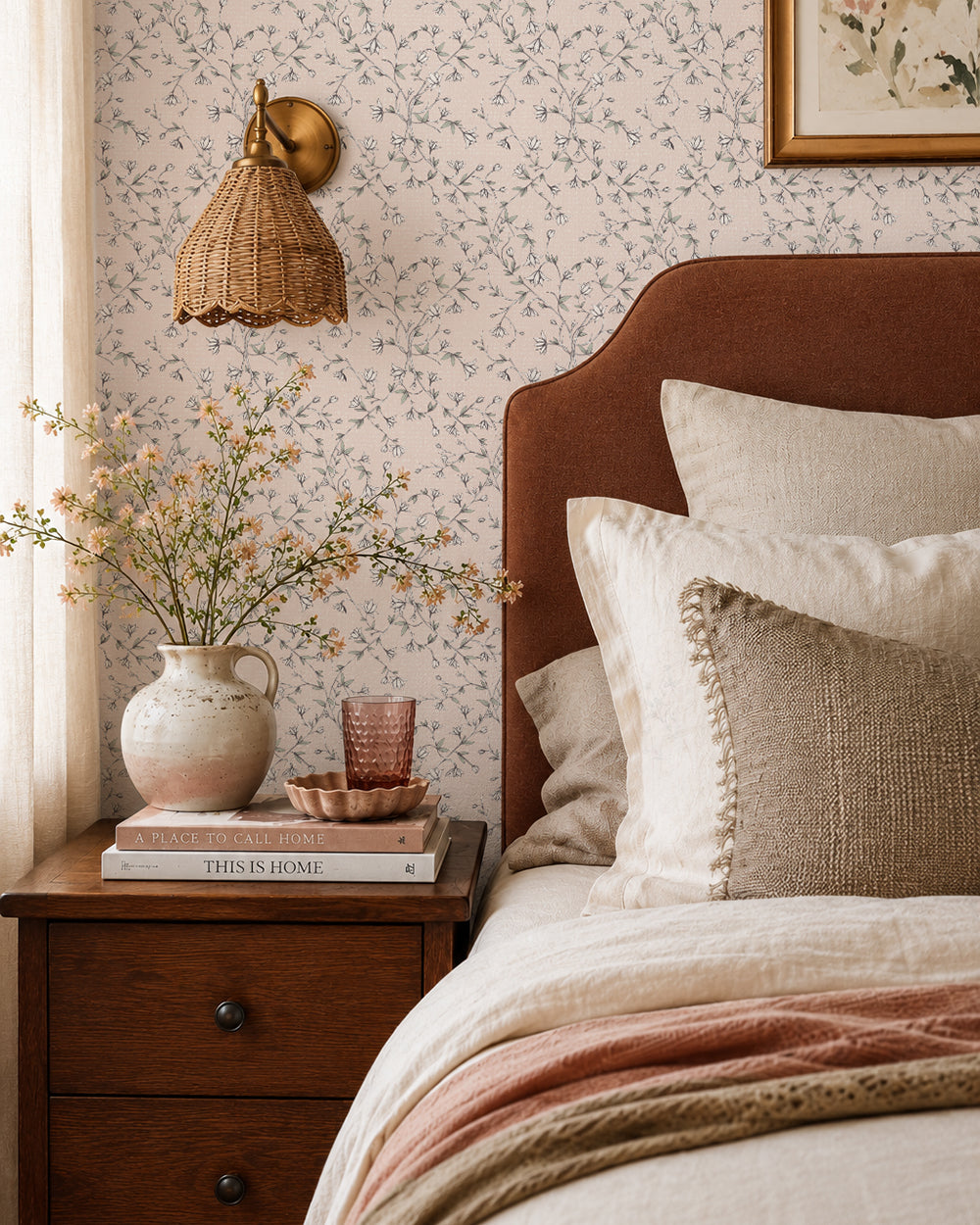 Spring Vine Blush wallpaper in a warm bedroom with a rust headboard, cream bedding and dark wood furniture.