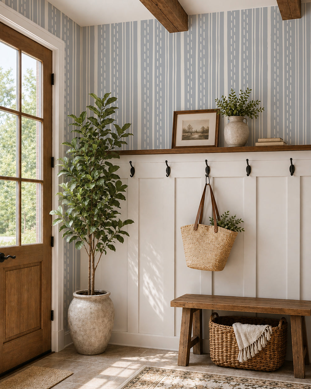 Ticking Stripe Dusty Blue wallpaper in a cozy entryway with white paneling, a wood bench and leafy plant.